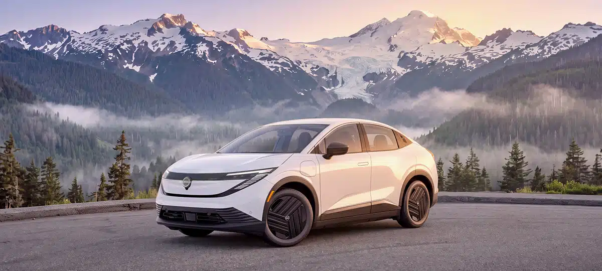 La Nissan Leaf blanche 2027 vue de 3/4 devant la montagne enneigée